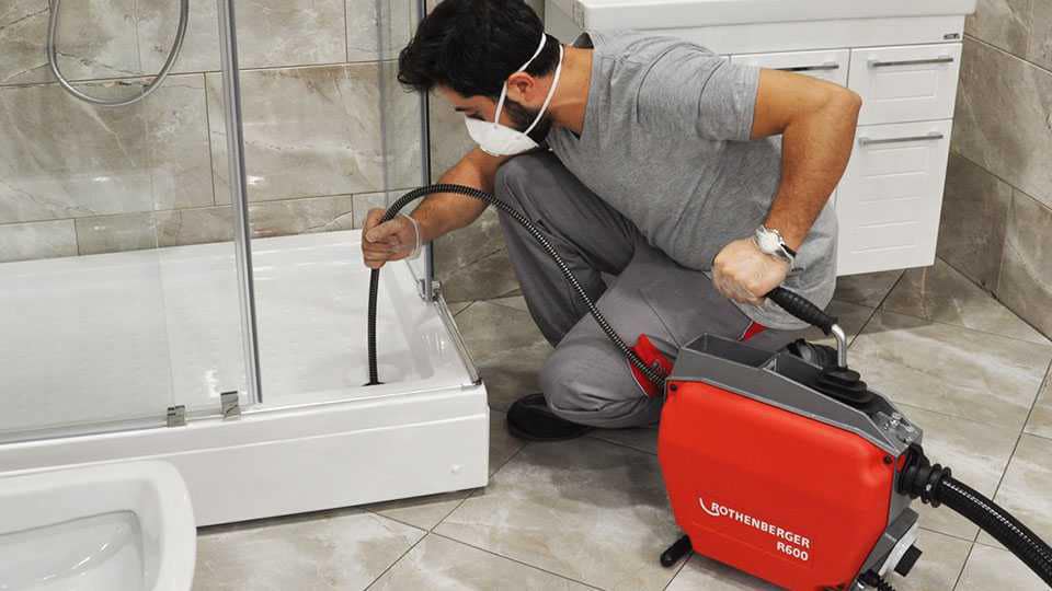 Técnico a desentupir sanita de hóspedes com mola elétrica profissional Rothenberger R600 sem partir azulejo
